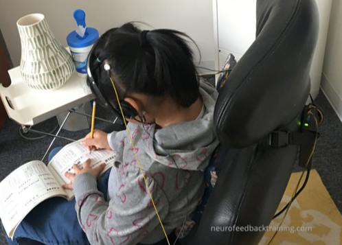 child doing homework during a neurofeedback session in nyc office at Neurofeedback Training Co.