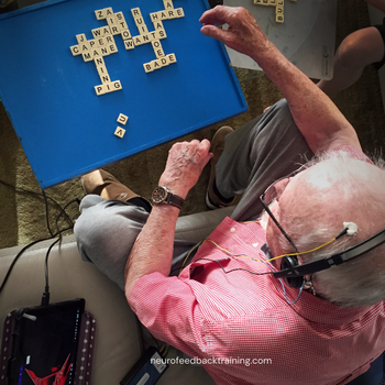 senior man playing a word game while doing a neurofeedback at home session